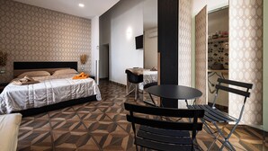 A hotel room with a bed, a small table with chairs, a mirror, and a patterned floor. - PIGNASECCA GUEST HOUSE  (Naples)