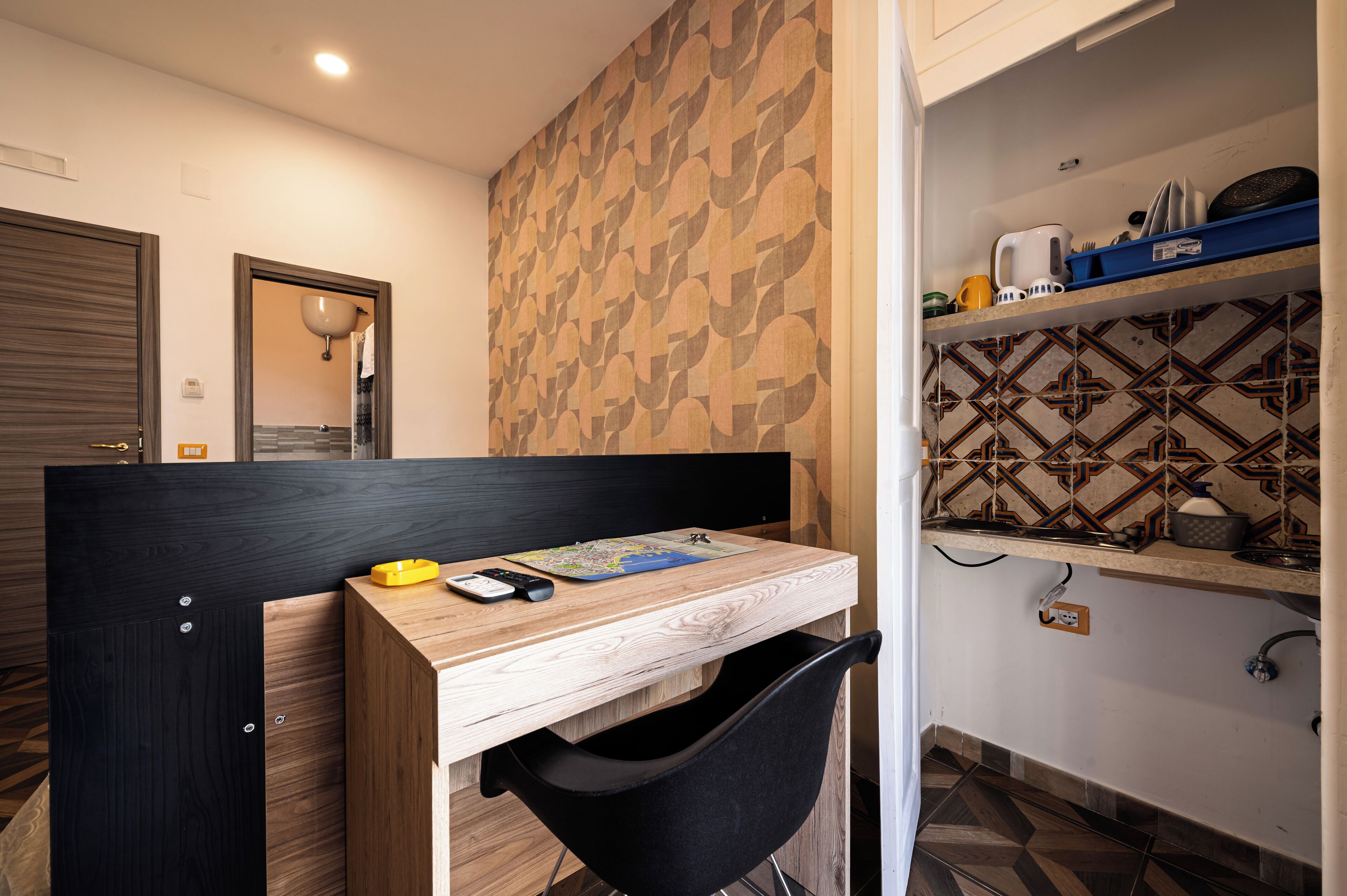 A compact room with a wooden desk, a black chair, a map, a phone, and a small yellow object.