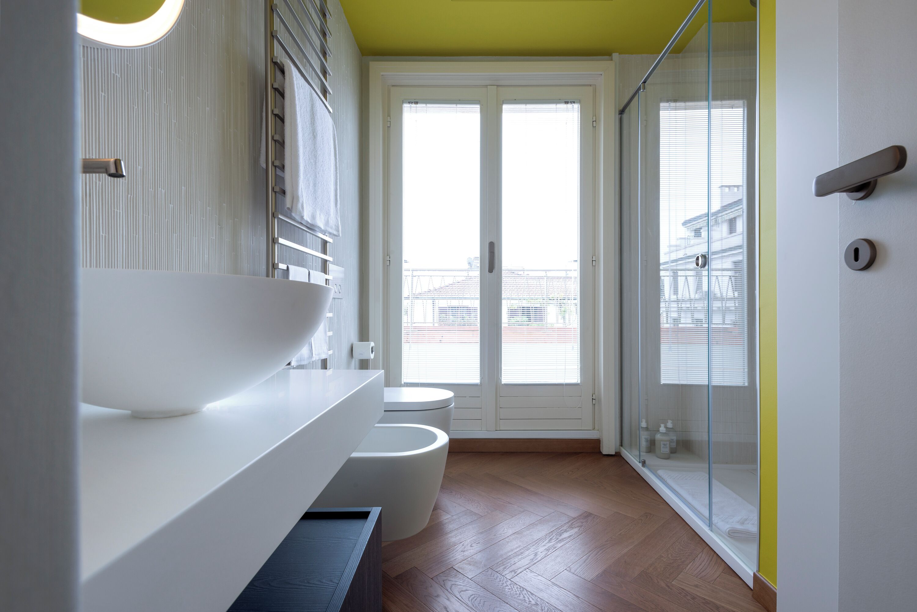 A modern bathroom with a large white basin, a toilet, and a glass-enclosed shower.