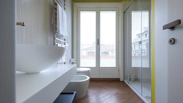 A modern bathroom with a large white basin, a toilet, and a glass-enclosed shower.
