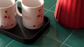 Two white mugs with red designs on a black tray on a green tiled countertop.