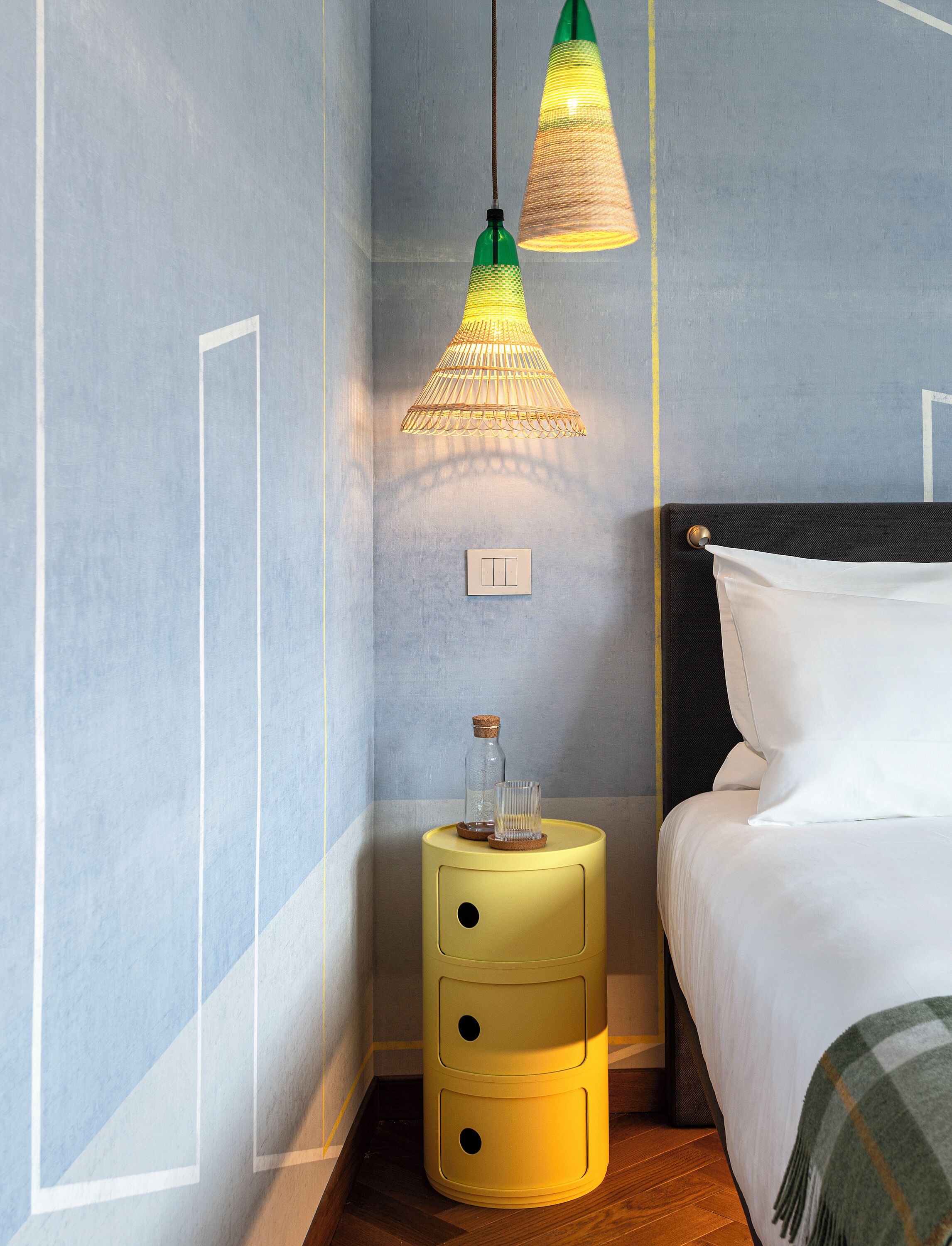 Una camera da letto ordinata con un letto, comodini e lampade a sospensione.