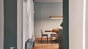 A hallway with a wooden floor, a dining area with a table and chairs, and a hanging light fixture. - DOMYA - Manzoni 25 (Milan)