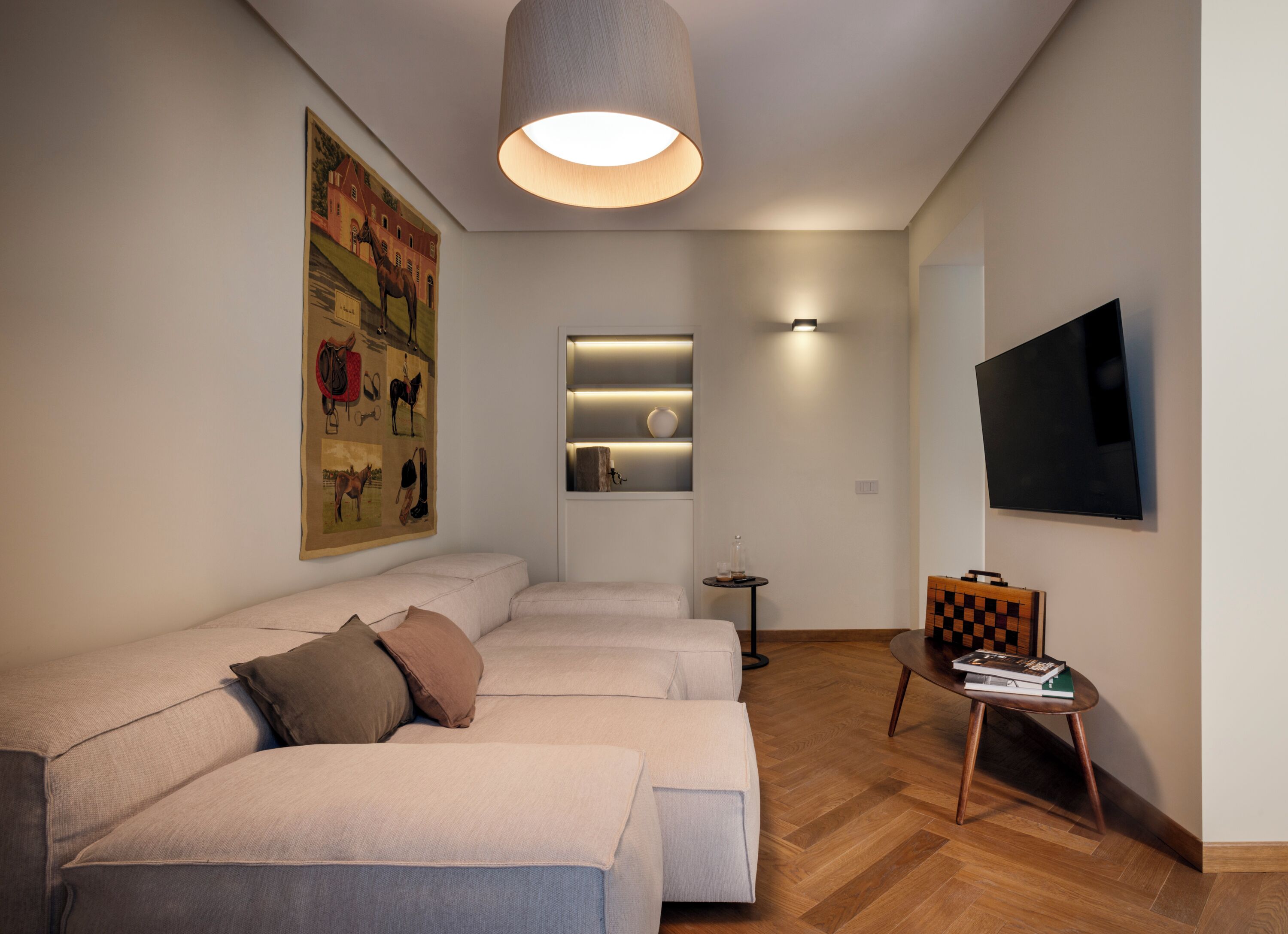 Una sala de estar moderna con un sofá, un televisor montado y un tablero de ajedrez.