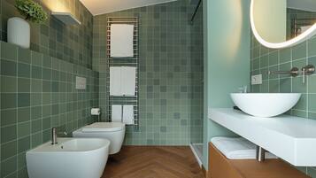 Une salle de bain avec un lavabo blanc, deux bidet, des toilettes et un miroir avec un éclairage intégré.