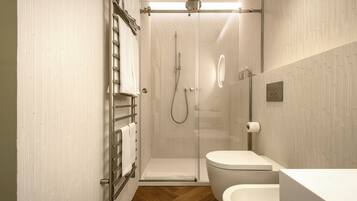Ein modernes Badezimmer mit einer gläsernen Duschkabine, einer weißen Toilette und einem Holzboden.