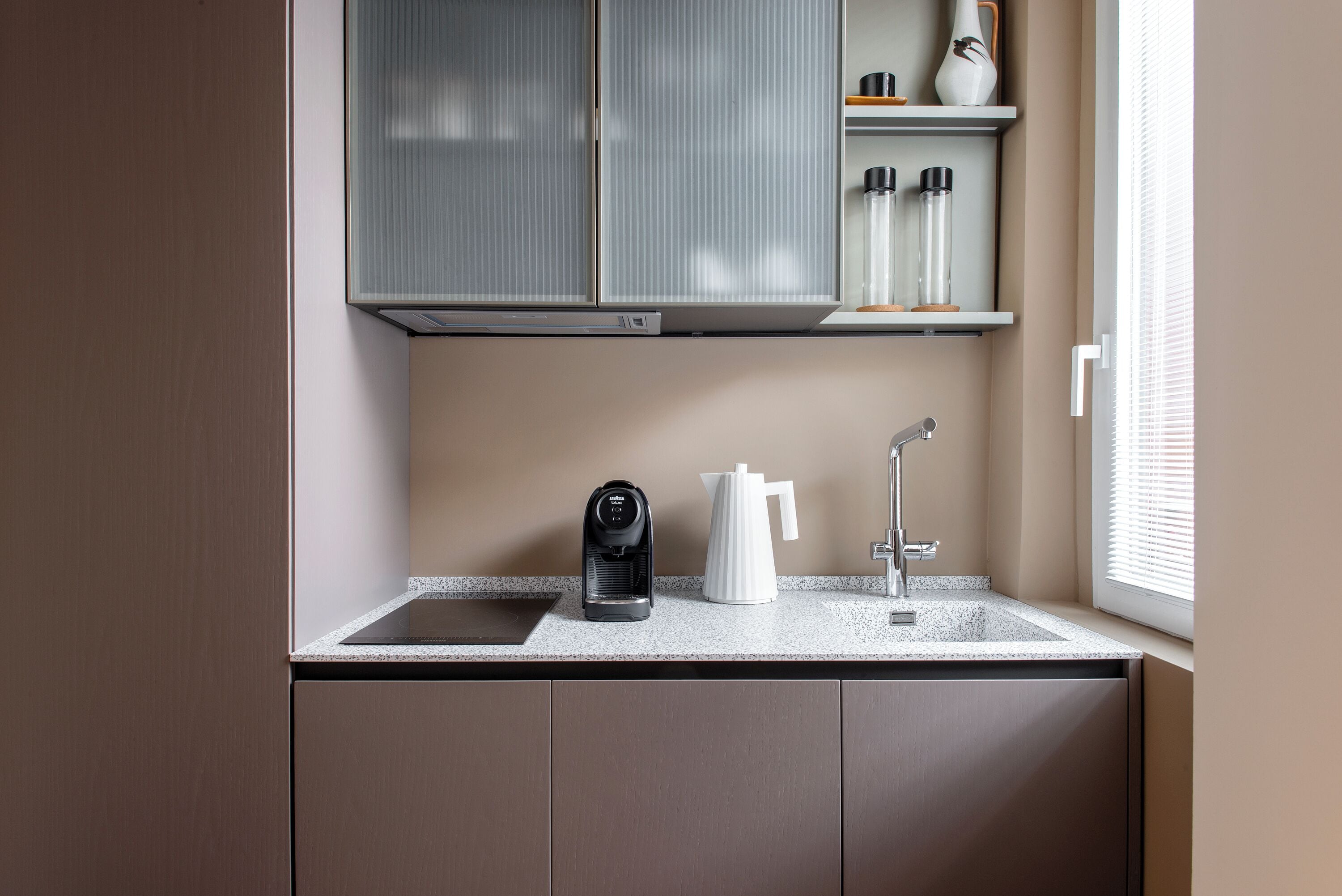 Una cocina compacta equipada con cafetera integrada, hervidor y pileta.