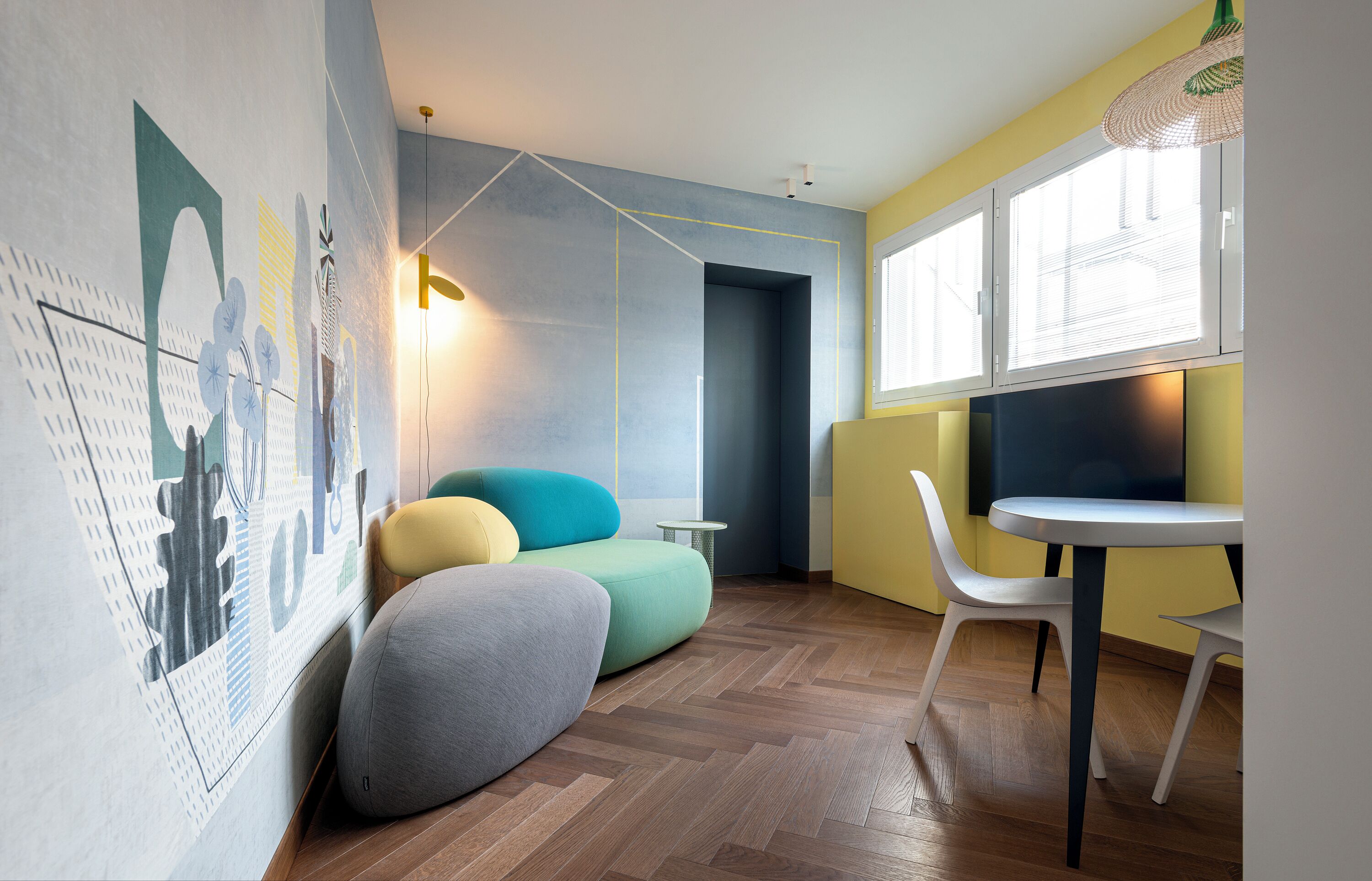 Ein modernes Zimmer mit Holzboden, einem runden Tisch, einer Couch und einem Sessel.