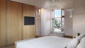 A bedroom with a large bed, wooden wardrobe, and a TV on the wall. - DOMYA - Manzoni 25 (Milan)