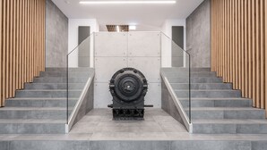 Un escalier moderne avec des rampes en verre, flanqué de lattes en bois et de marches en pierre grise.
