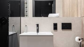 A modern bathroom with a white sink, a toilet, and a mirror.