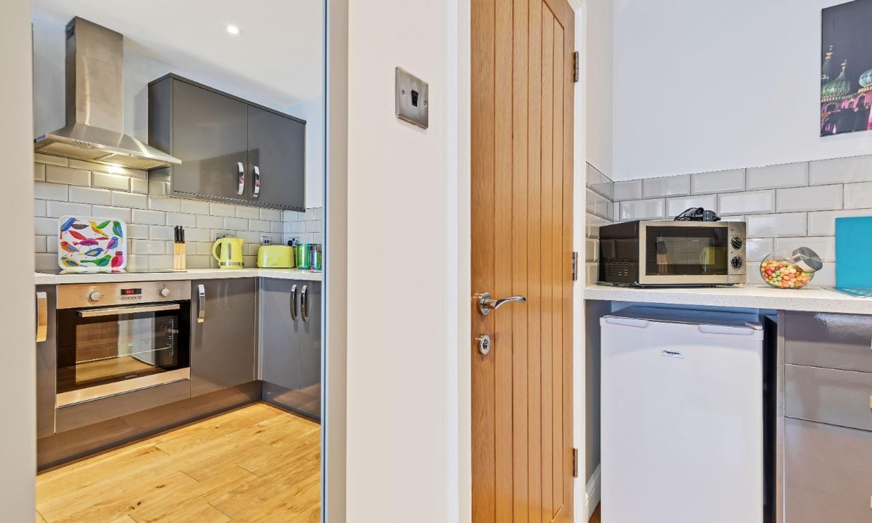 A compact kitchen with a microwave, kettle, and oven.