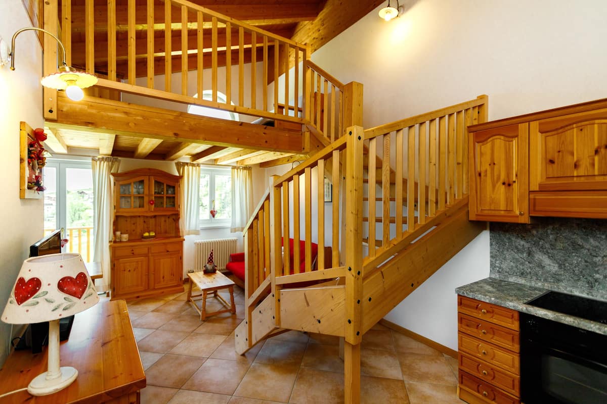 Un escalier en bois menant à un niveau supérieur, une cuisine dotée de plans de travail en granit et un coin repas avec une table et des chaises.