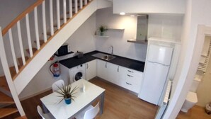A compact kitchen with a built-in washing machine, a refrigerator, and a dining area with a table and chairs. - Apartment - 2 Bedrooms - 8951 (La Aparecida, Cantabria)