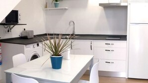 A modern kitchen with white cabinets, a sink, and a countertop. There is a blue pot with a plant on the table, and a washing machine in the background. - Apartment - 2 Bedrooms - 8951 (La Aparecida, Cantabria)