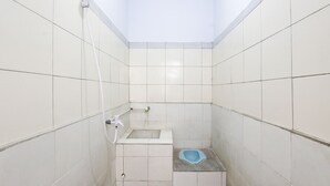 A small, tiled bathroom with a shower, a toilet, and a sink. - SPOT ON 93717 Nayus Homestay Syariah 4 (Yogyakarta)