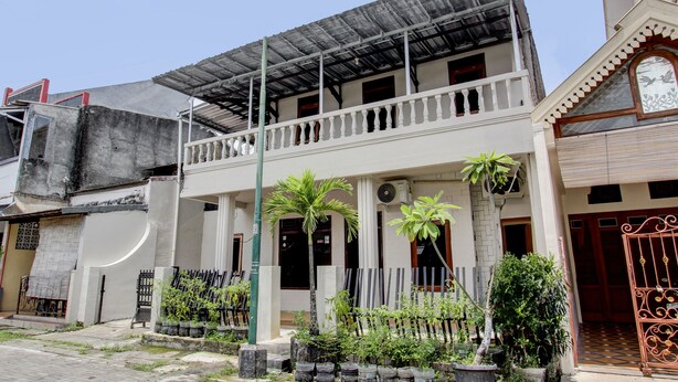 A two-story building with a balcony, potted plants, and a gated entrance. - SPOT ON 93717 Nayus Homestay Syariah 4 (Yogyakarta)
