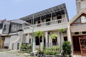 A two-story building with a balcony, potted plants, and a gated entrance. - SPOT ON 93717 Nayus Homestay Syariah 4 (Yogyakarta)