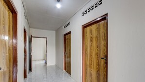 A hallway with wooden doors and white tiled flooring. - SPOT ON 93717 Nayus Homestay Syariah 4 (Yogyakarta)