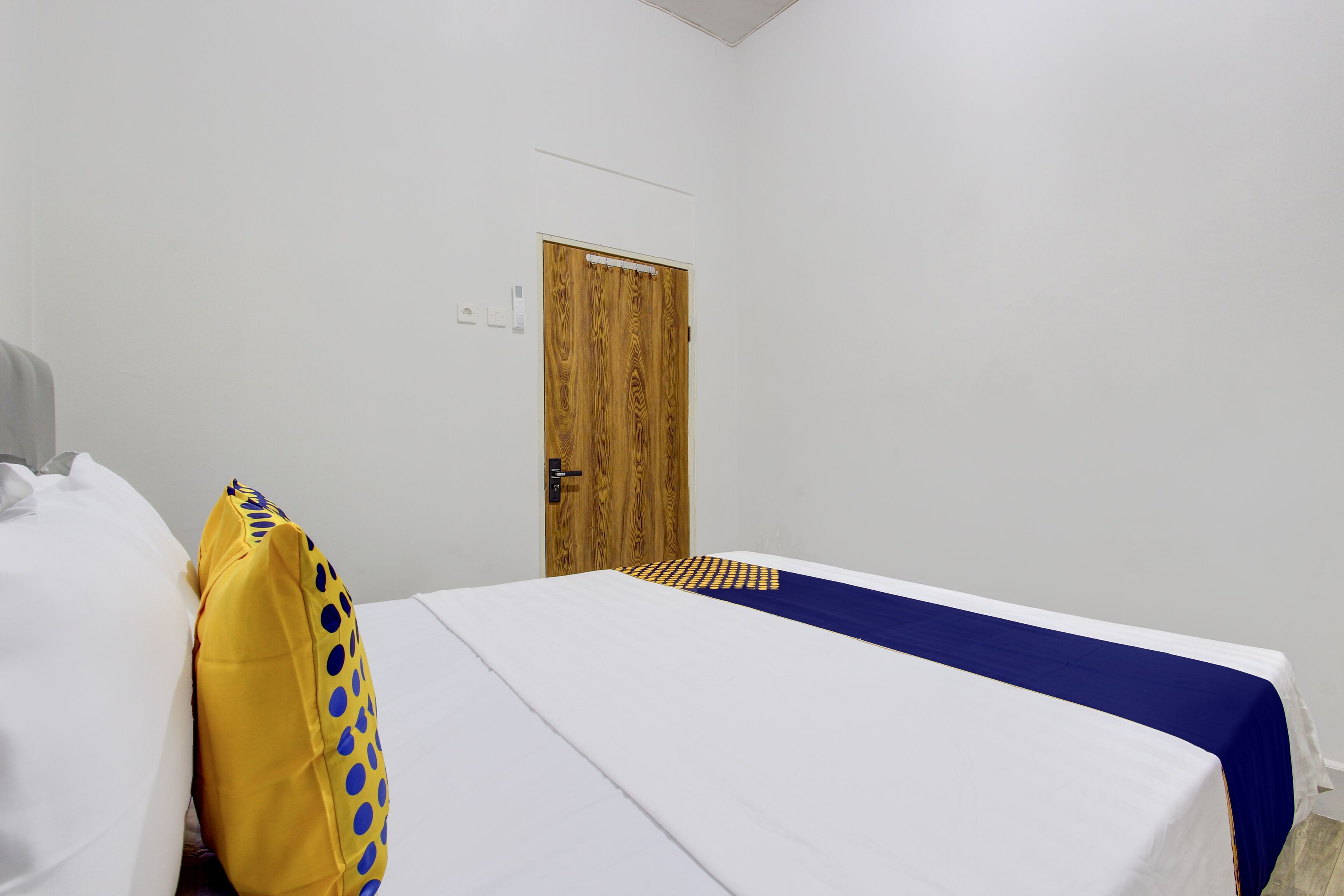 A room with a bed, a wooden door, and a white wall.