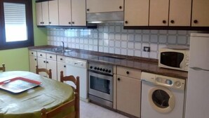 A compact kitchen with a sink, stove, microwave, and washing machine. - Apartment 3 Bedrooms with WiFi and Sea views (Portonovo)