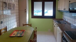 A compact kitchen with a dining area, featuring a window with blinds, a sink, and cabinets. - Apartment 3 Bedrooms with WiFi and Sea views (Portonovo)