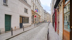 Une rue pavée bordée de bâtiments historiques, un drapeau et une pancarte indiquant « fermé ».