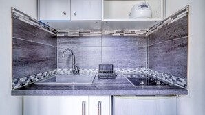Une cuisine de taille réduite, équipée d’une cuisinière intégrée, d’un évier et d’un robinet.