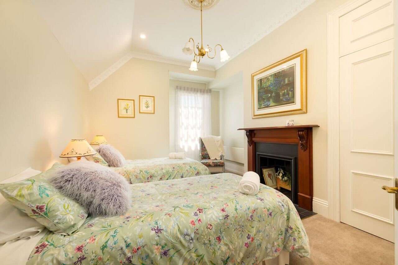 A bedroom with two beds, a fireplace, and a chandelier.