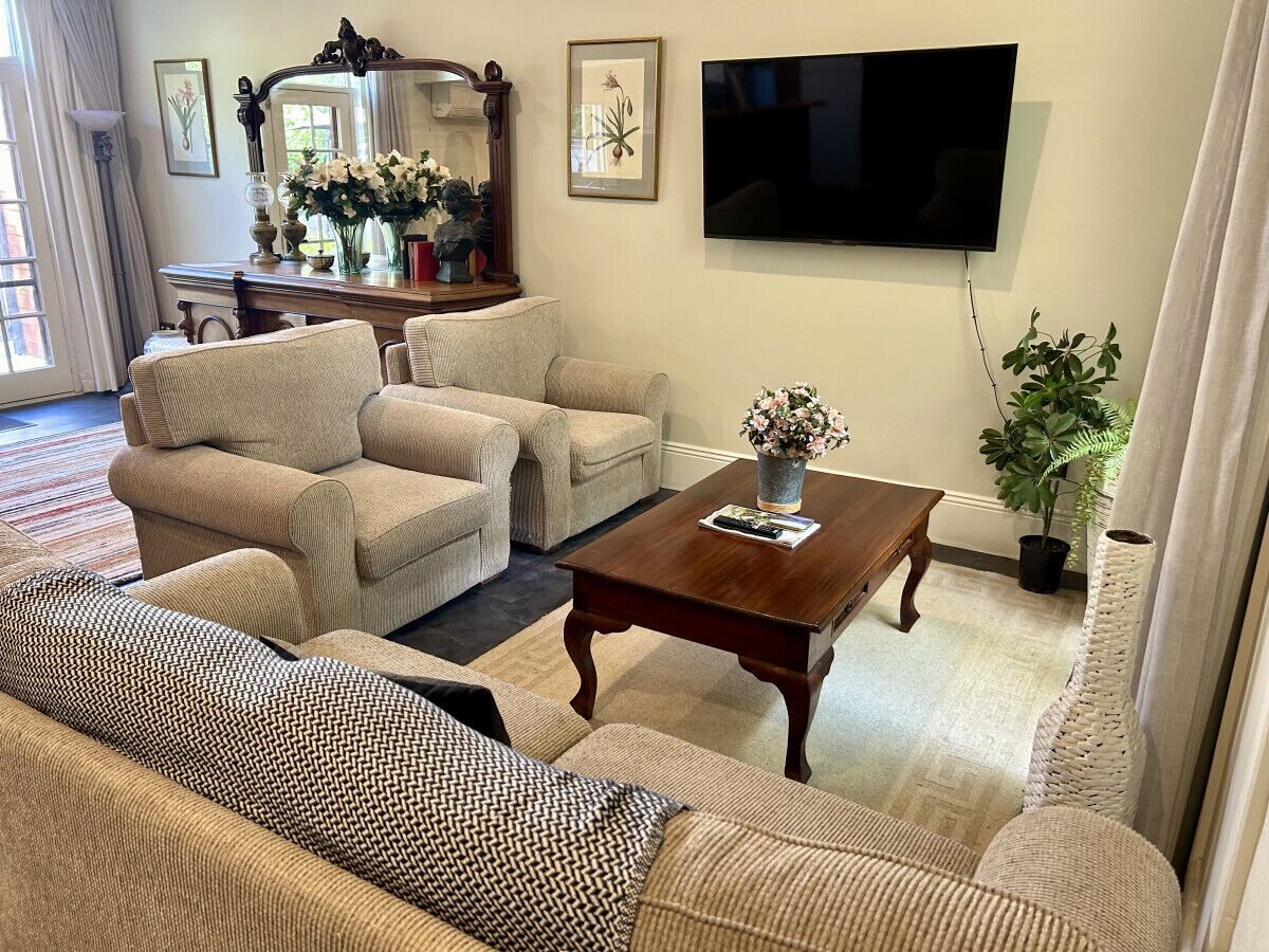 Una sala de estar con un sofá, dos sillones, una mesa de centro, un televisor y una planta en maceta.
