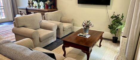Una sala de estar con un sofá, dos sillones, una mesa de centro, un televisor y una planta en maceta.
