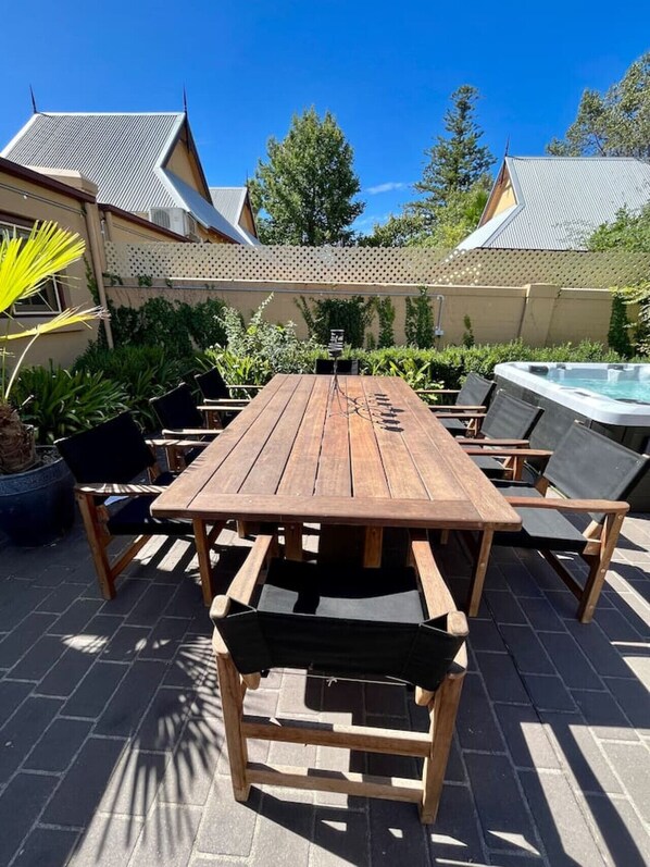 Una mesa de madera con sillas, un jacuzzi y una pérgola.