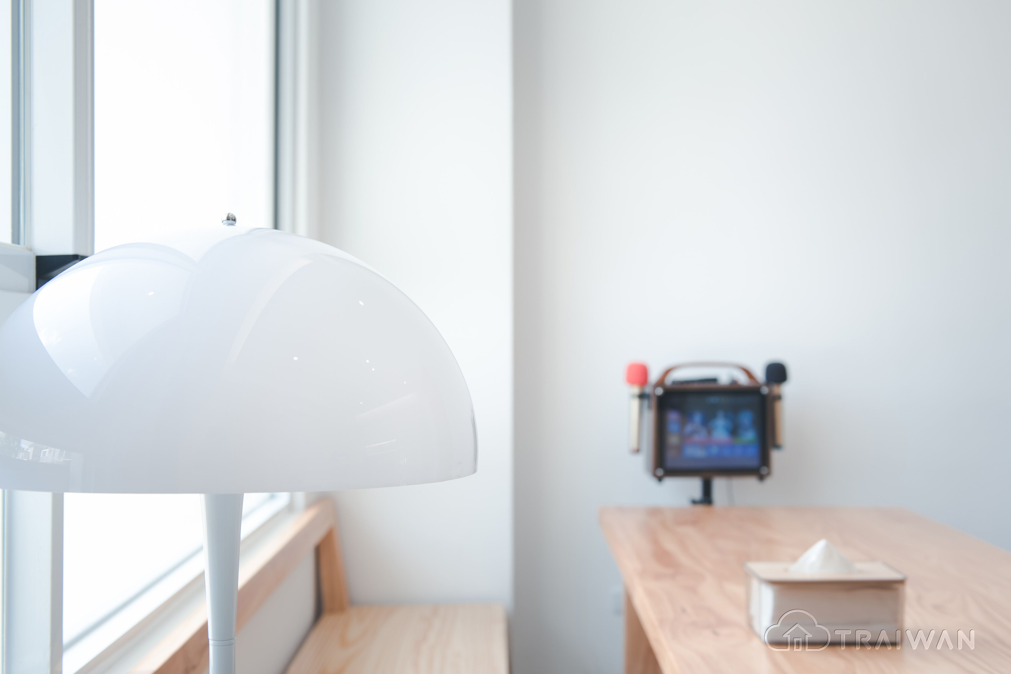 Una habitación moderna con una lámpara blanca, una mesa de madera y una caja pequeña sobre la mesa.