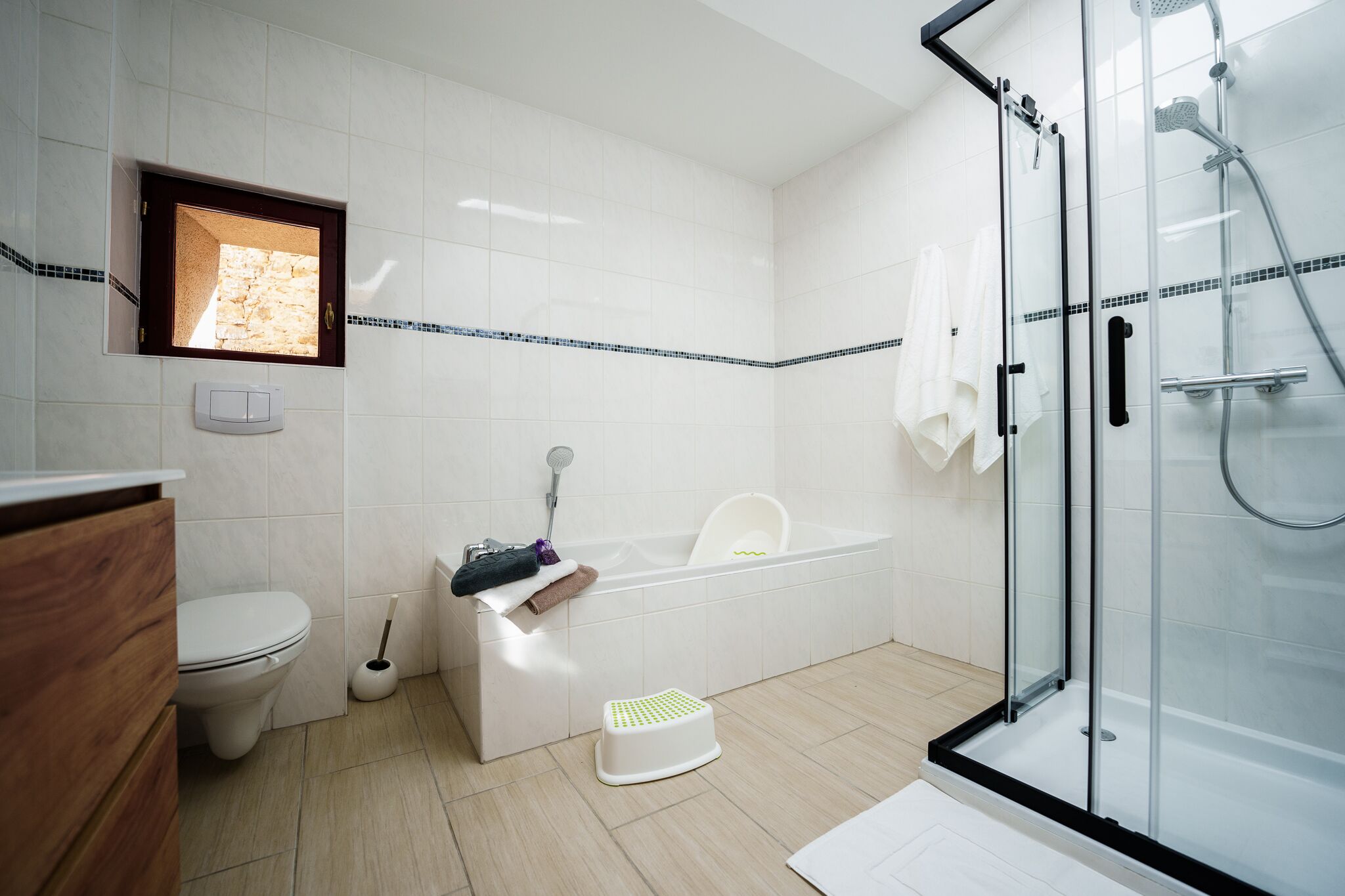 A modern bathroom with a toilet, sink, bathtub, and glass shower enclosure.