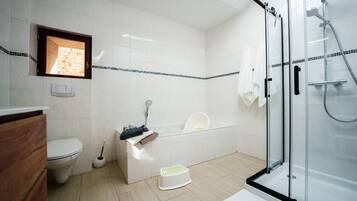 A modern bathroom with a toilet, sink, bathtub, and glass shower enclosure.