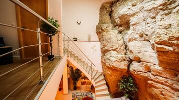 A multi-level interior with a staircase, a rock wall, and a wooden floor.