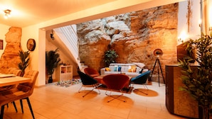 Un salon moderne avec un mur en pierre, un coin repas avec une table et des chaises en bois, et un espace salon confortable avec un canapé et des fauteuils.