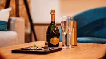 A bottle of Ruinart champagne and two glasses on a wooden table.