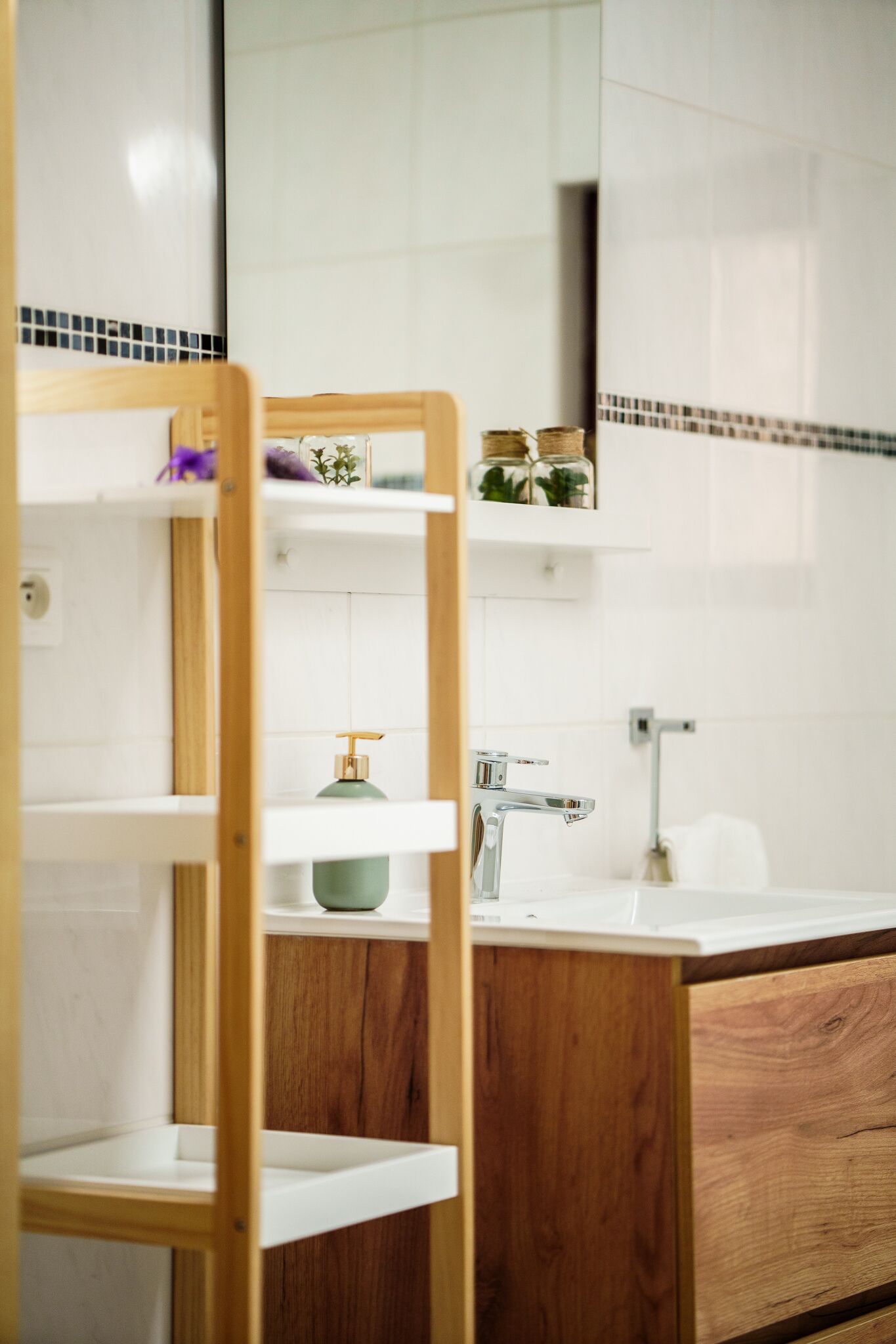 A bathroom with a wooden shelf, a green soap dispenser, and a white sink.