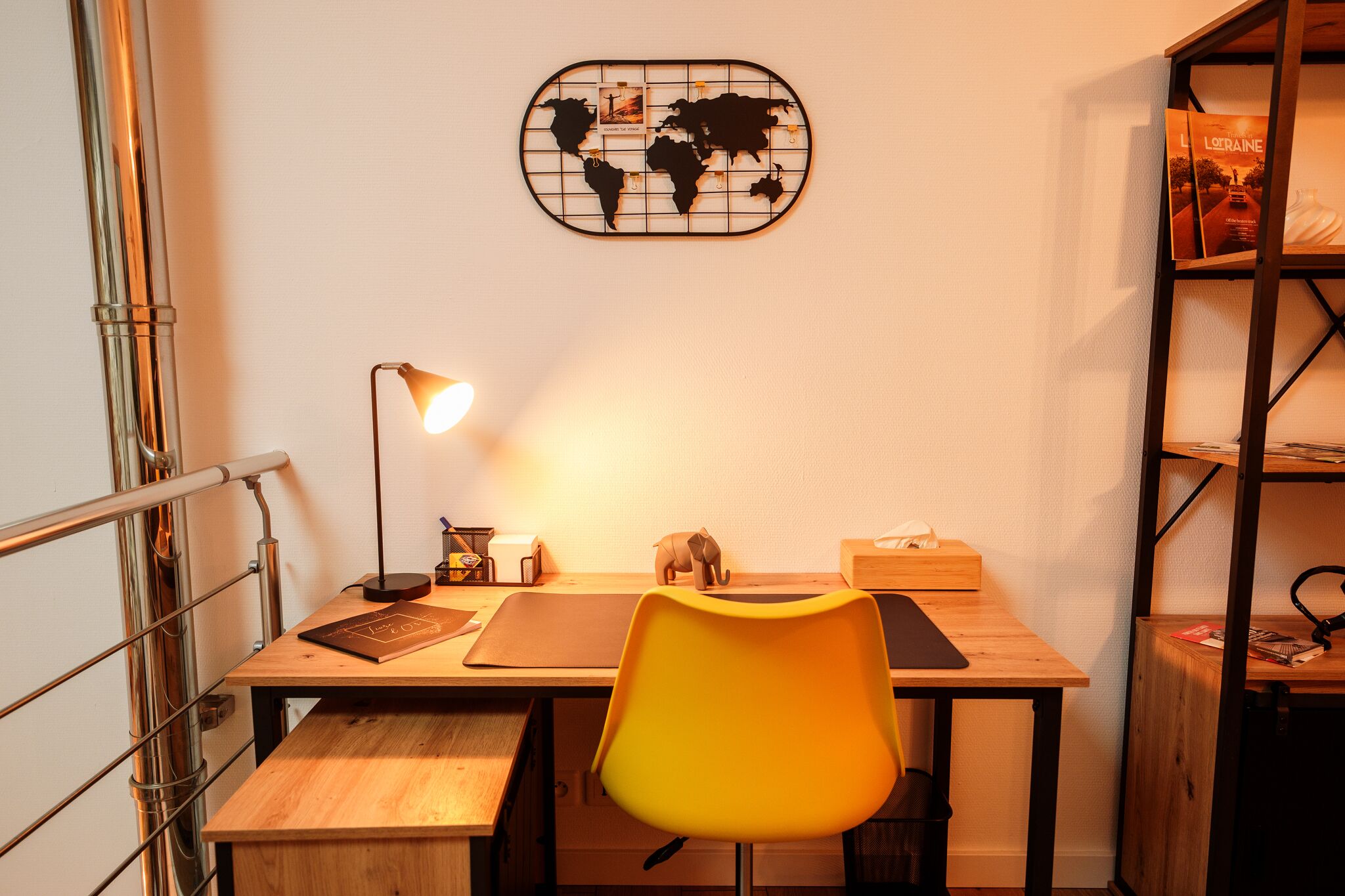 En arbetsplats med ett skrivbord, en stol, en lampa och en världskarta som dekoration.