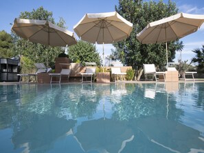 A swimming pool with lounge chairs and umbrellas.