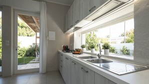 A modern kitchen with a large window, white cabinetry, and a built-in oven.