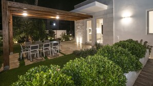 A modern house with a patio, outdoor seating, and well-maintained landscaping.