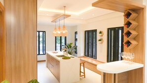 A modern kitchen with a central island, pendant lighting, and a wine rack. - Villa Ferrer (Mahatao)