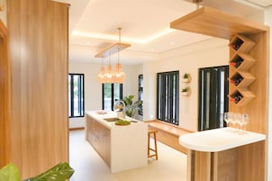 Una cocina moderna con una isla central, iluminación colgante y una estantería para vinos.