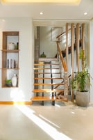 Una escalera con barandillas de madera y una planta en maceta a la derecha.