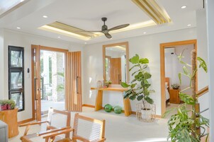 Una habitación de hotel moderna con ventilador de techo, ventanas amplias y un escritorio de madera.