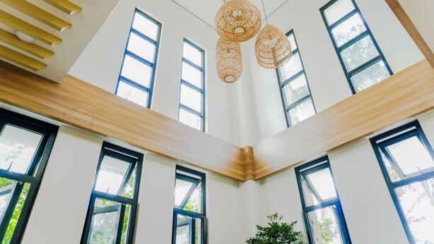 A high-ceiling room with large windows and hanging wicker light fixtures. - Villa Ferrer (Mahatao)