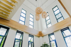 Una habitación con techos altos, ventanas grandes y lámparas de mimbre colgantes.