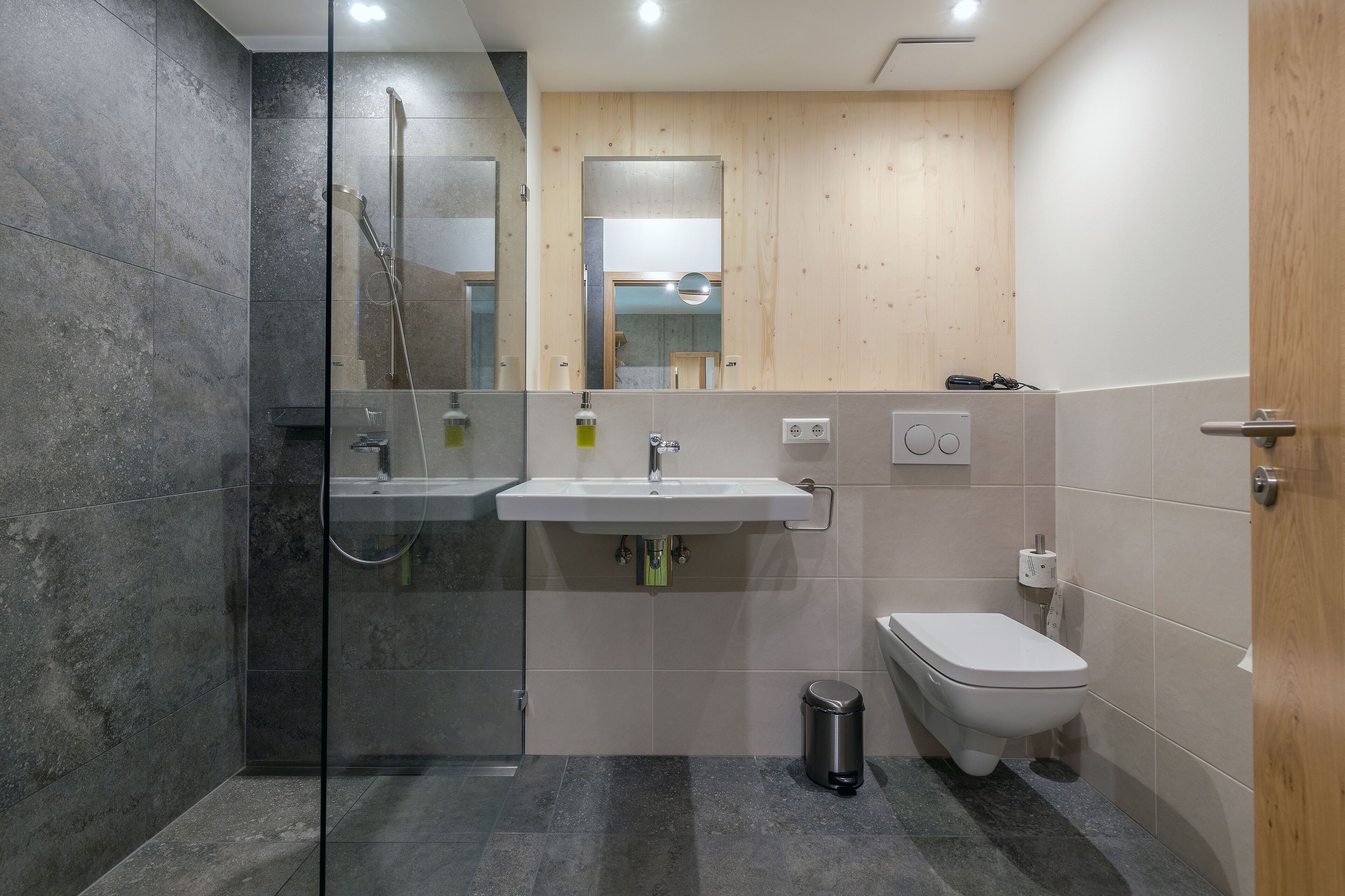 Een moderne badkamer met een douchecabine van glas, een wastafel en een toilet.